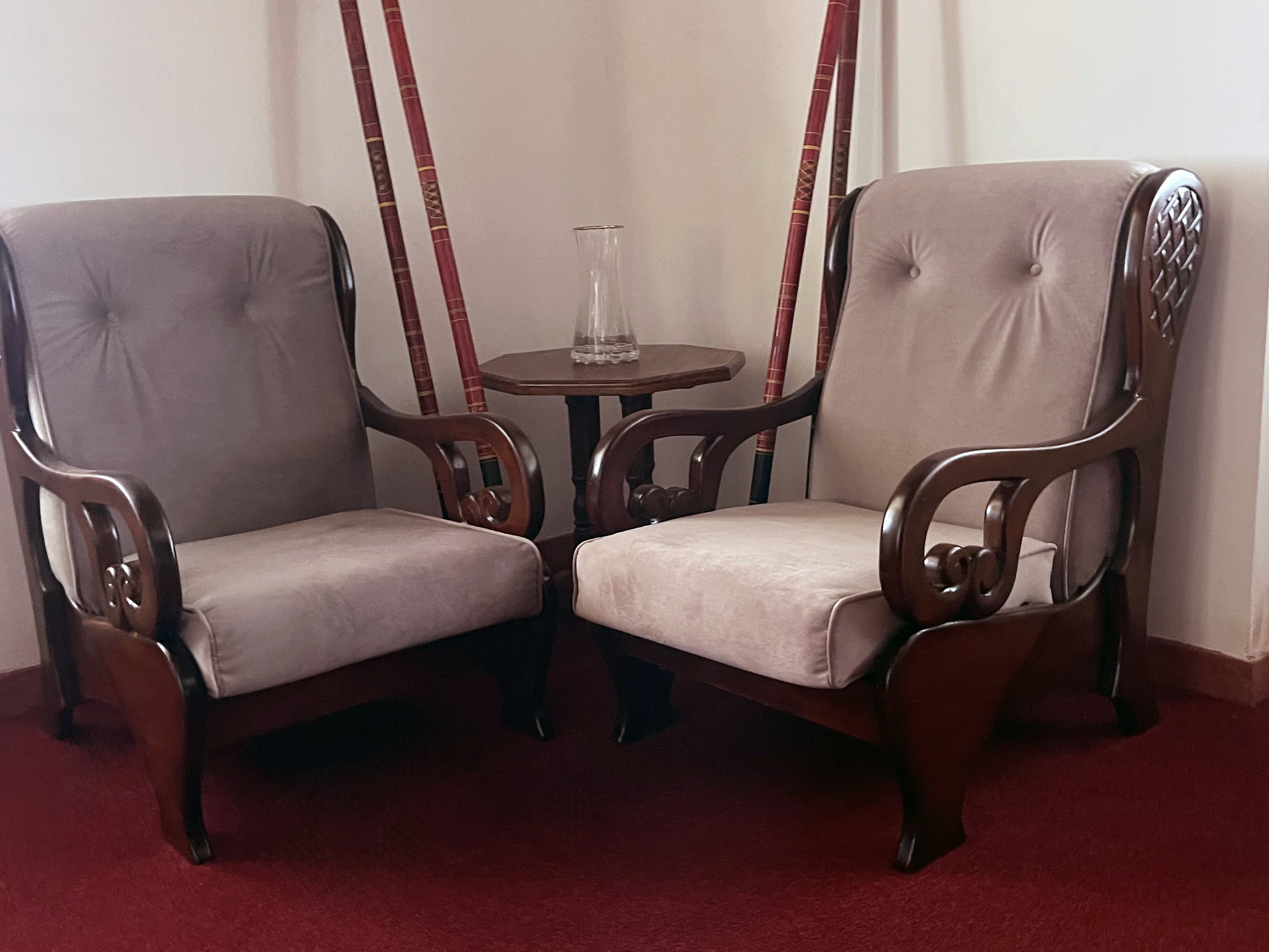 A cozy corner in the living area at Lavinrich Hotel, Horana featuring elegant wooden armchairs and a classic side table, perfect for quiet conversations or a relaxing tea break.